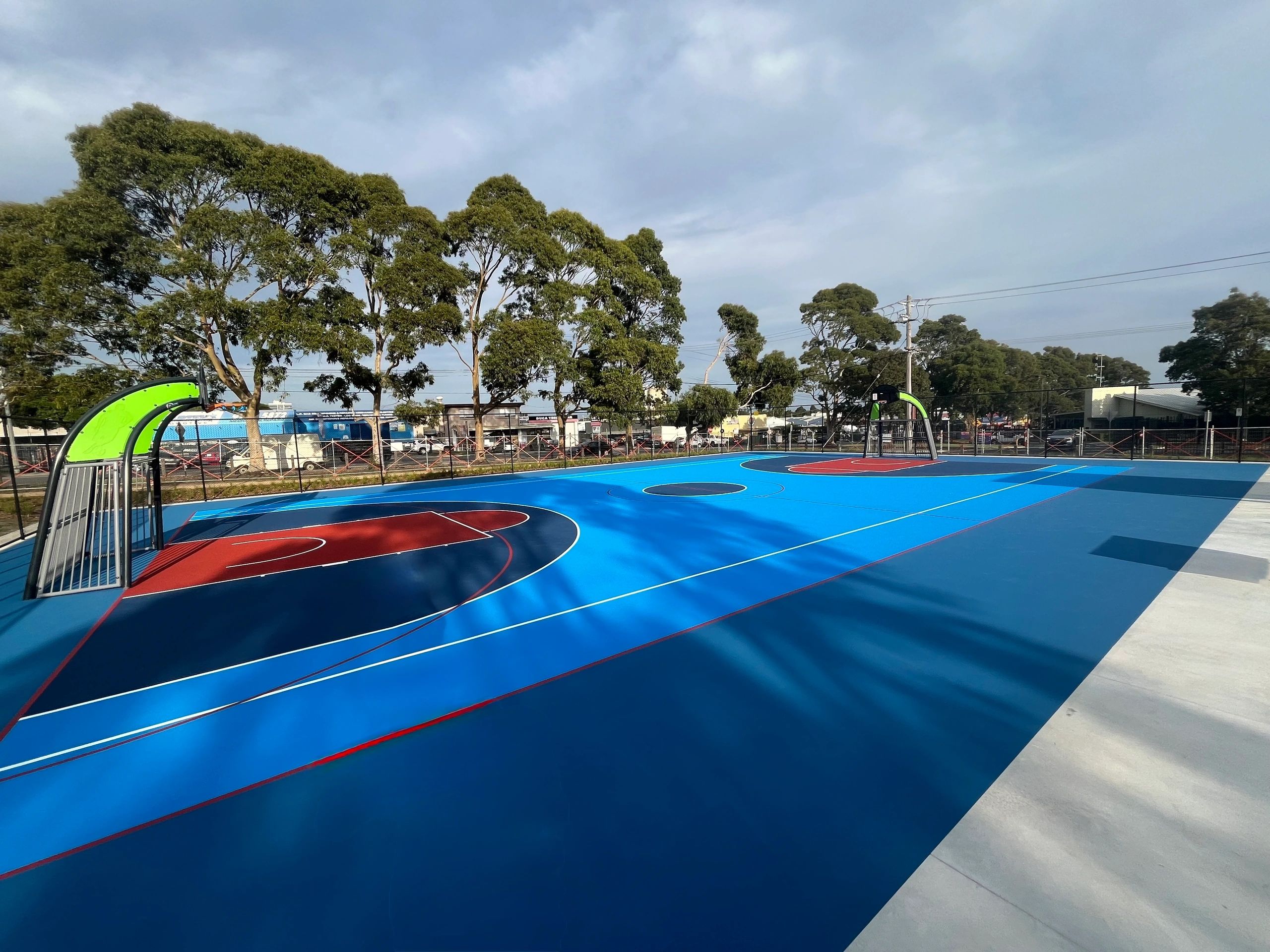 Colorful outdoor basketball court with green hoops and seating under clear sky.