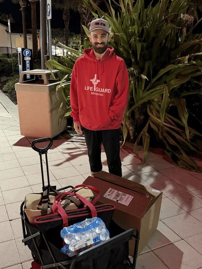 LifeGuard Ministries ministering at night with a cart full of bags and boxes spreading Gods love.