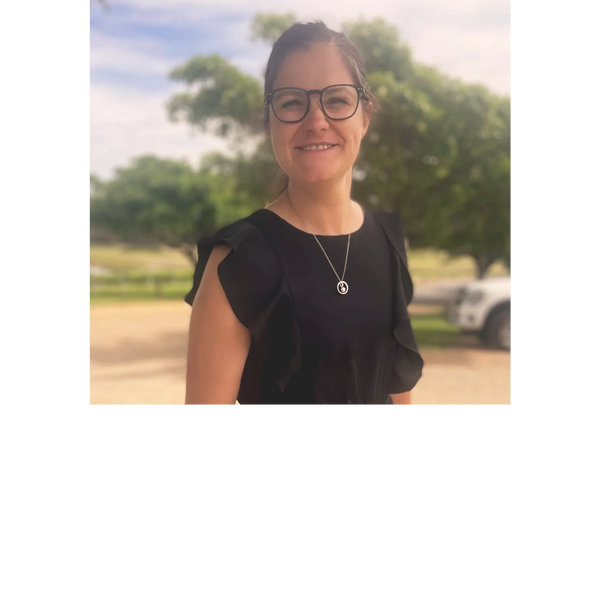 Smiling woman wearing glasses and a black dress outdoors.