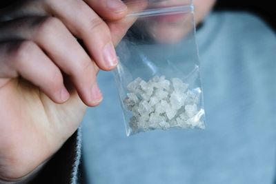 Close-up of hand holding a small plastic bag of crystal methamphetamine (ice) during intervention