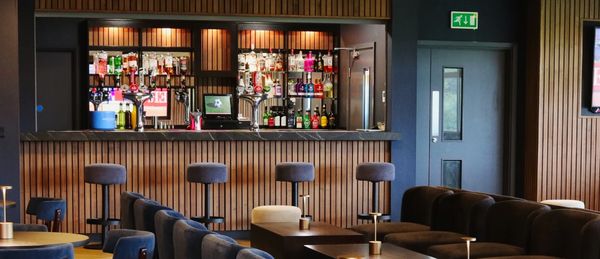 Inside the Farrare Lounge Suite of Bangor City Football club. Theres a bar, wood cladded walls 