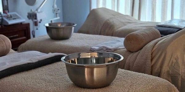 Two metal bowls on spa beds with towels and pillows.