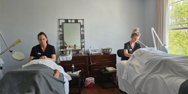 Two women giving spa treatments in a serene room.