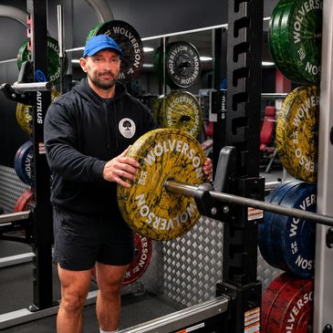 Man holding weight plate in gym, ready to lift.