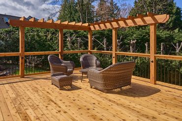 beautiful cedar deck with large timber arbor and wood railing with black spindles.