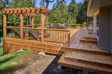 wide view of large and beautiful cedar custom deck with timber arbor and lattice.