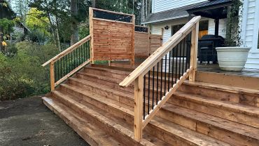 Newly built wooden stairs with black metal railings and privacy panels.
