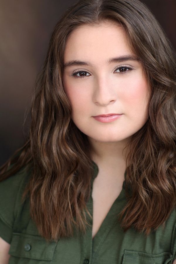Close-up portrait of a young woman with wavy brown hair and a calm expression.