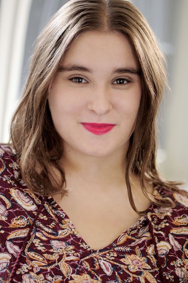Young woman with a warm smile and patterned top.