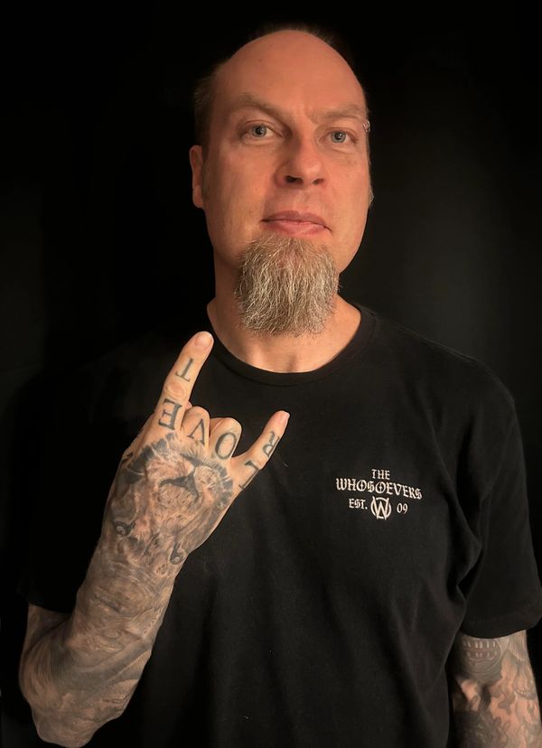 Man with tattoos showing rock hand sign.