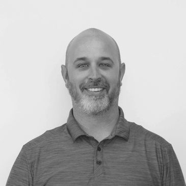 Smiling bald man with a beard in a casual polo shirt.