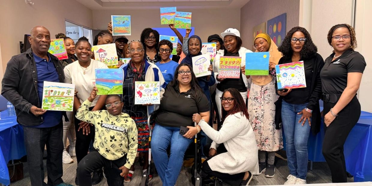 Group holding colorful paintings, smiling happily.