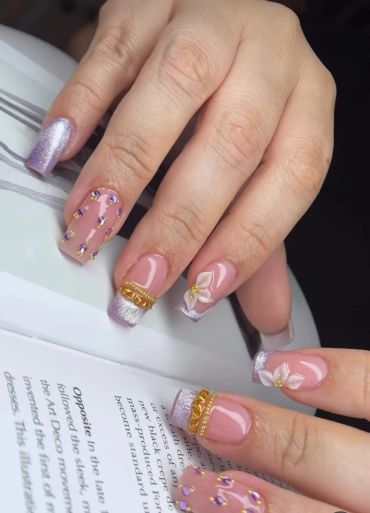 Elegant pastel purple and nude nails with floral and jeweled designs.