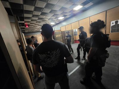 Group of people in a dimly lit indoor shooting range.