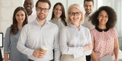 A diverse group of smiling professionals posing confidently in an office.