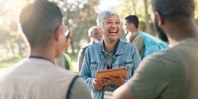 A joyful woman engaging in conversation with two men outdoors.