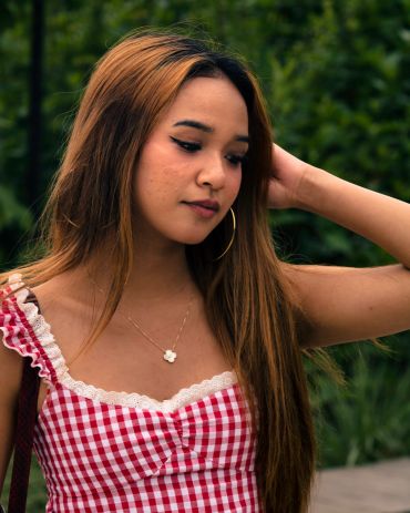 Young woman in a red checkered dress with long hair.