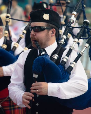 Man playing bagpipes in traditional attire.
