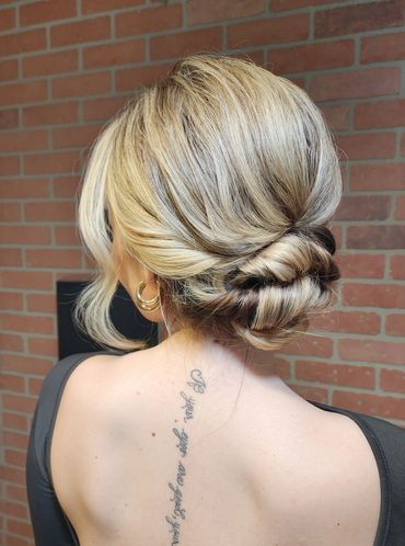 Elegant blonde updo hairstyle with a tattoo on the back.