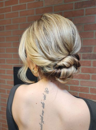 Elegant blonde updo hairstyle with a tattoo on the back.