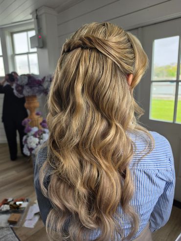 Blonde hair styled with soft waves and a twisted half-up braid.