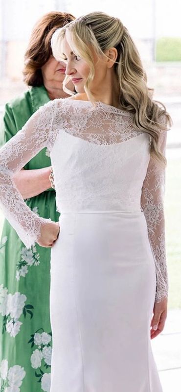 Bride in white lace wedding dress with woman in green dress.