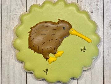 scalloped cookie with green icing and brown kiwi bird at center