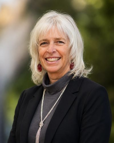 Smiling woman with white hair in professional attire.