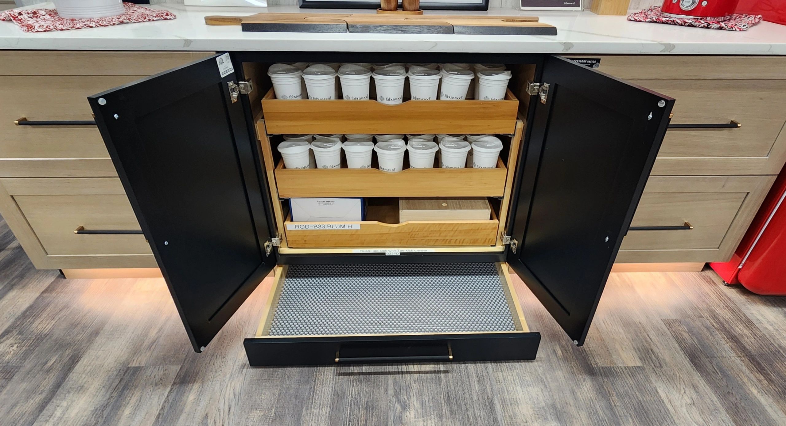 Open kitchen cabinet with neatly arranged cups and wooden drawers.