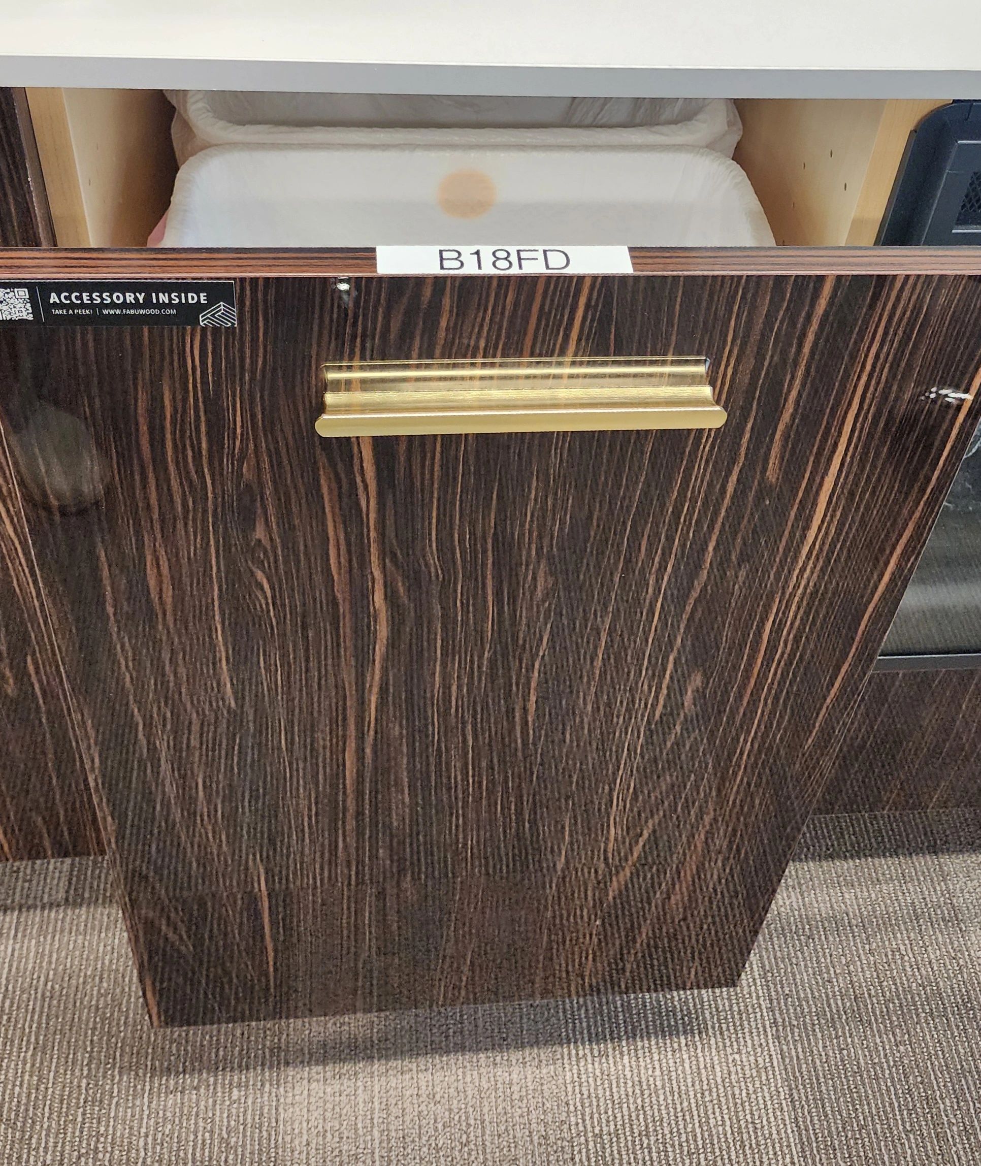 Dark wood cabinet drawer with gold handle.