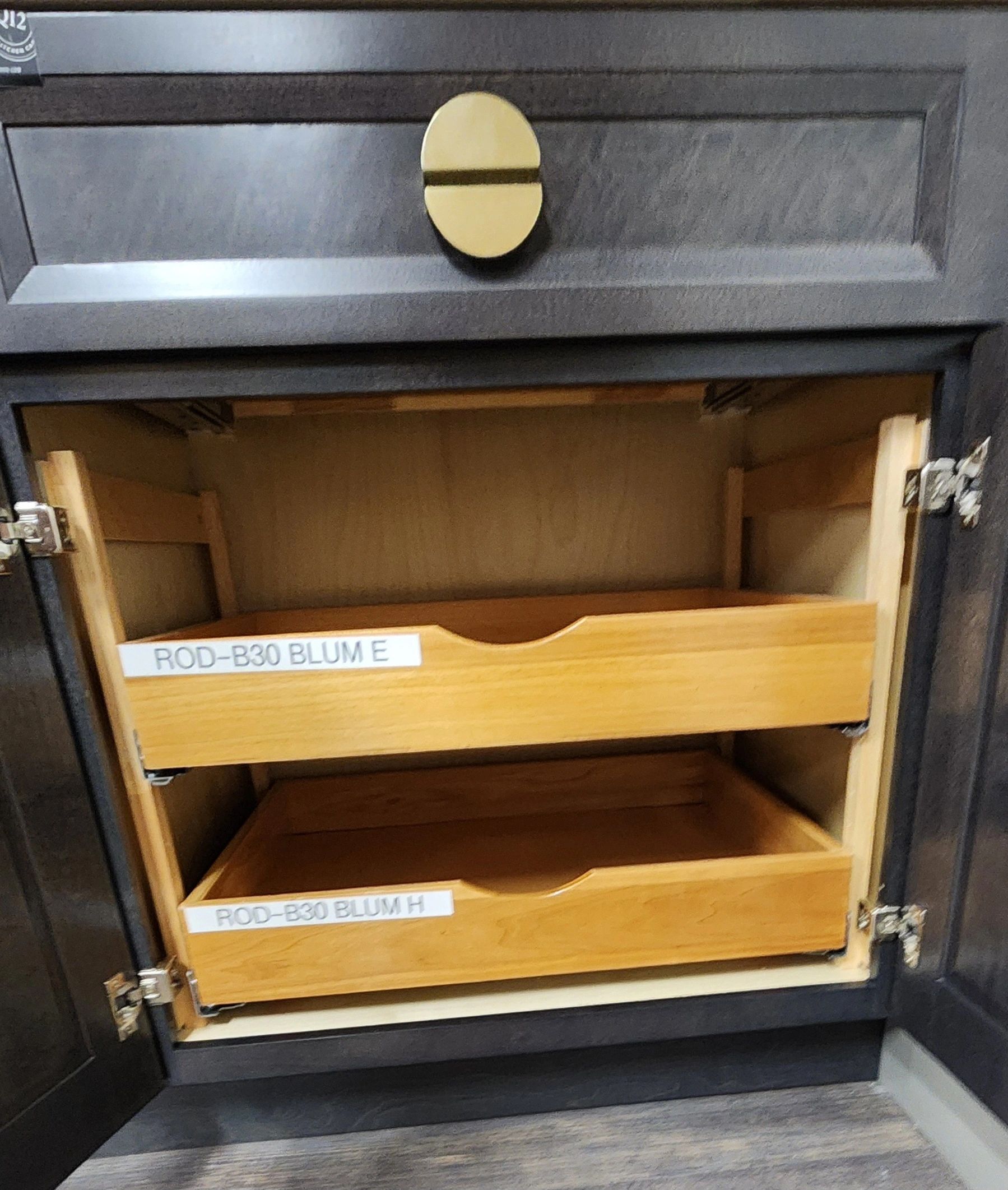 Open cabinet with wooden drawers labeled ROD-B30 BLUM E and H.