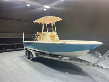 A blue and white boat on a trailer indoors under bright lights.