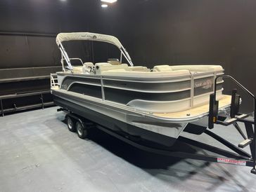 A pontoon boat on a trailer indoors with beige seats and a canopy.