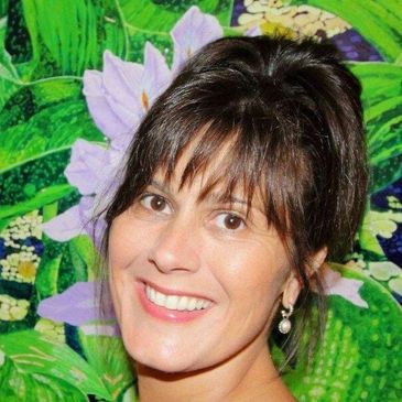 Smiling woman with dark hair and pearl earrings against a colorful floral background.