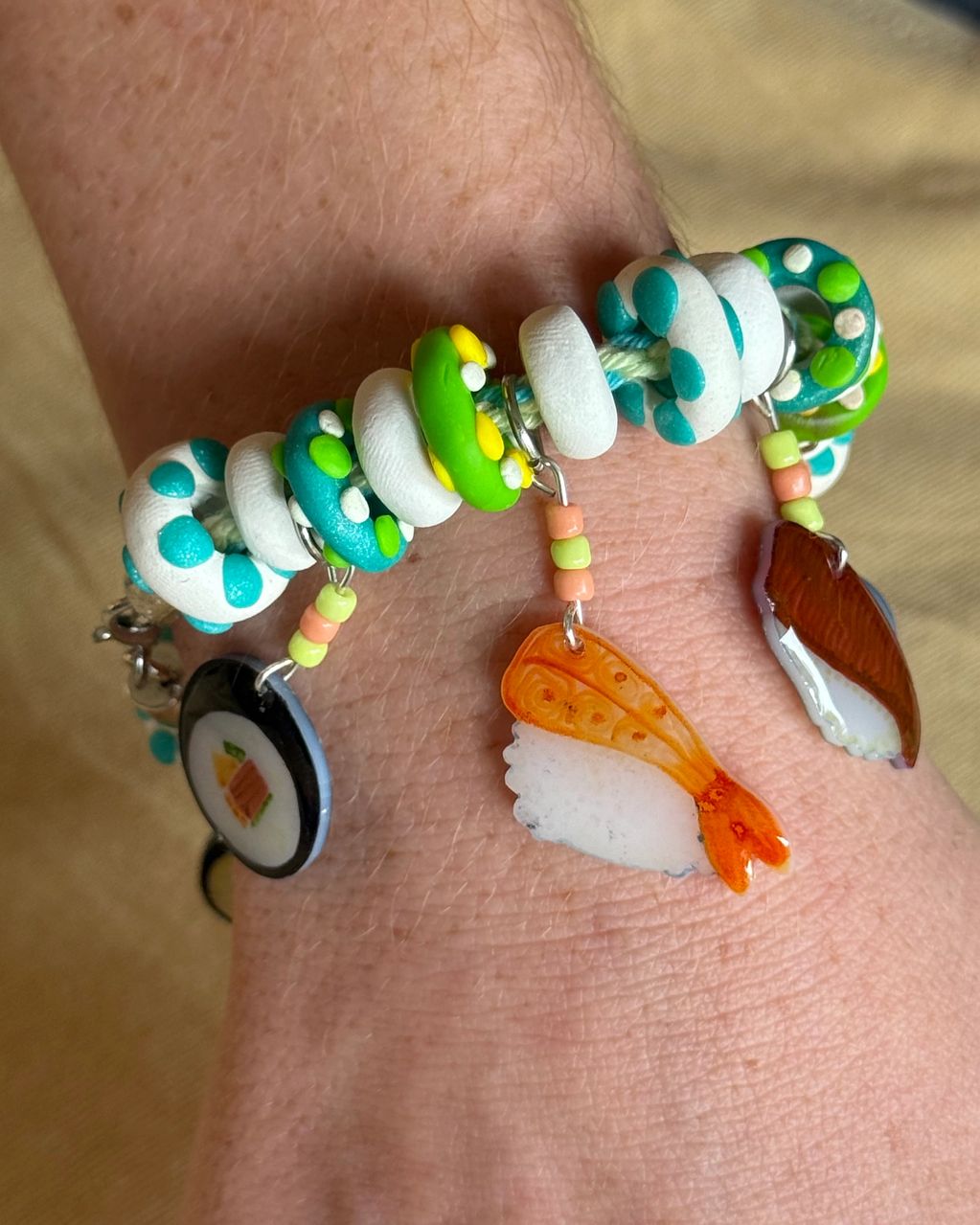 Colorful sushi-themed charm bracelet on a wrist.