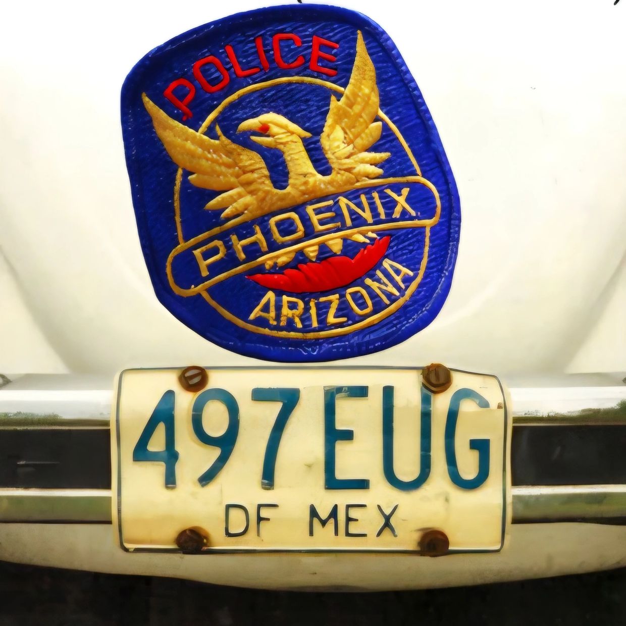 Vintage Phoenix, Arizona police badge on a car with a license plate.