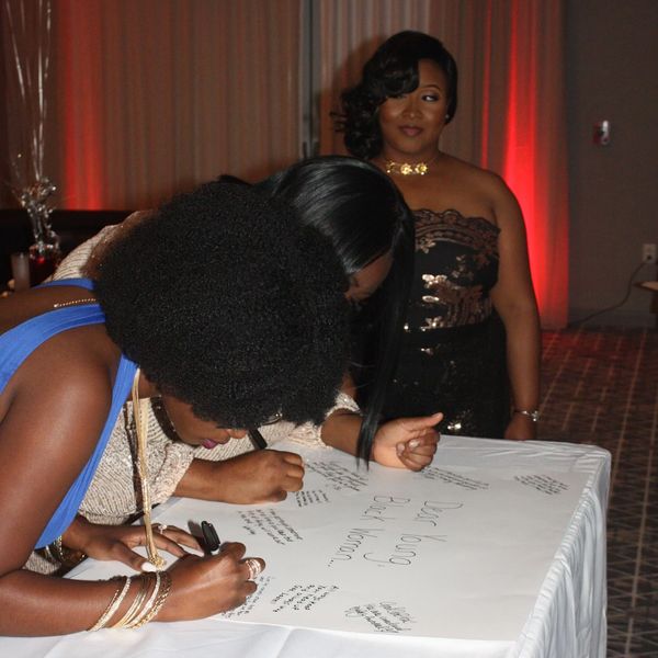 Women writing on white tablecloth.