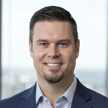 Smiling man in suit with a goatee.