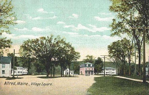 Village square in Alfred, Maine with trees and buildings under a blue sky.