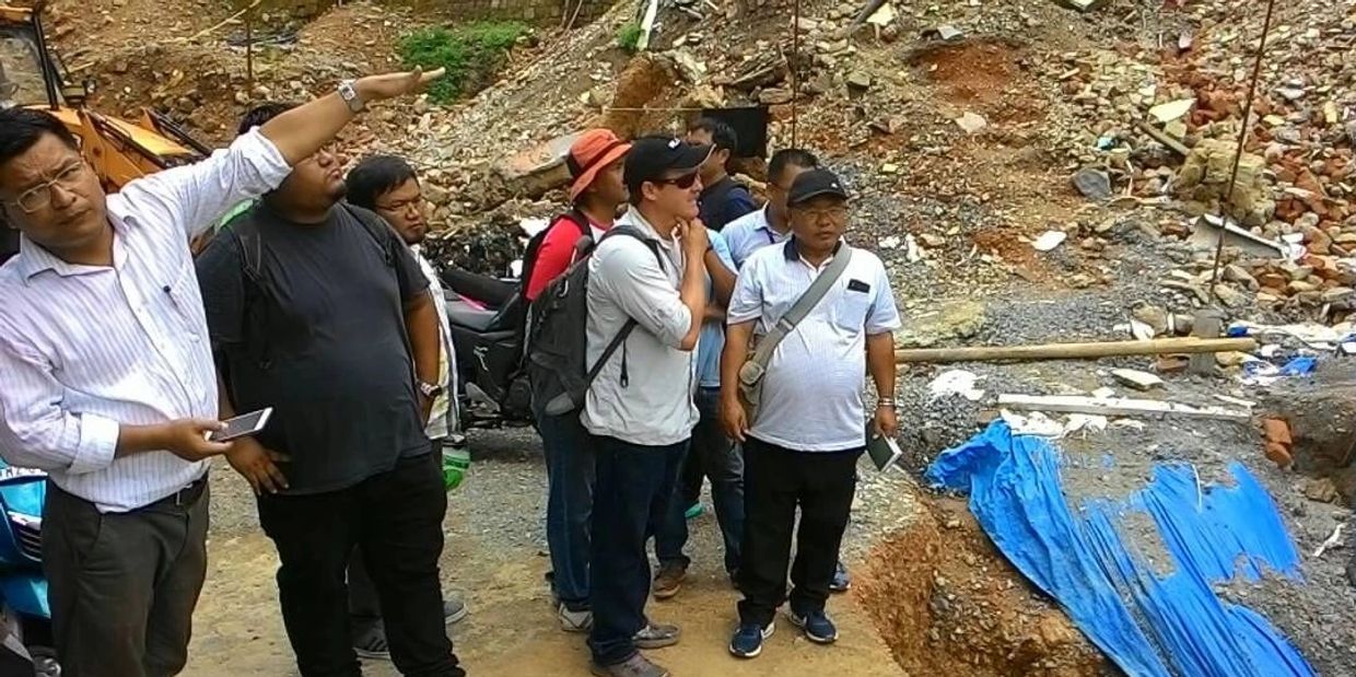 A group of government officials and members of GeoHazards Society looking at the damage caused by a 