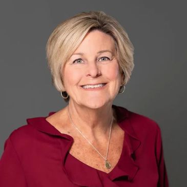 Smiling woman with short blonde hair wearing a red blouse.