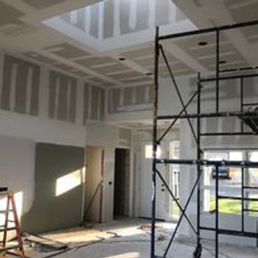 Interior of a house under construction with scaffolding and drywall installation.