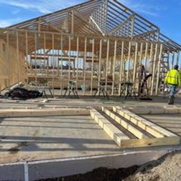 Wooden framework of a house under construction on a concrete foundation.