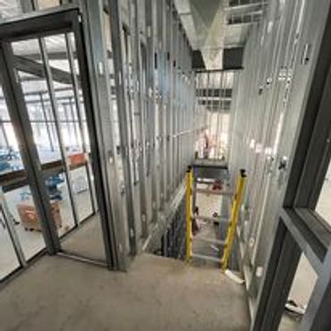 Interior view of a building under construction with metal framing and a ladder.