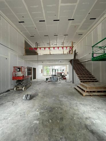 Interior view of an unfinished building under construction with stairs and equipment.