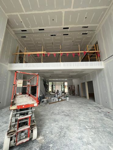 Interior of a building under construction with scaffolding and paint supplies.