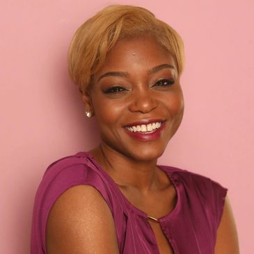 Smiling woman with short blonde hair against a pink background.