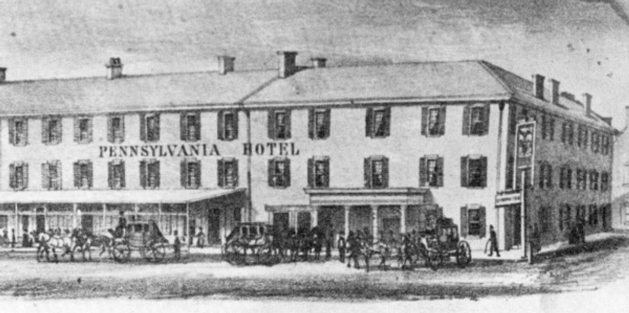 Historic Pennsylvania Hotel with horse-drawn carriages outside.