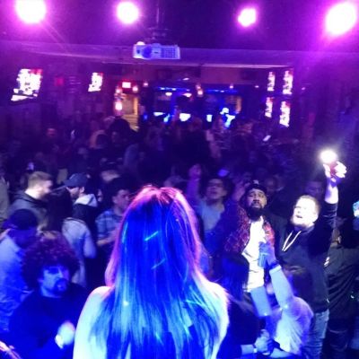 Back of a woman singing to a crowded nightclub.
