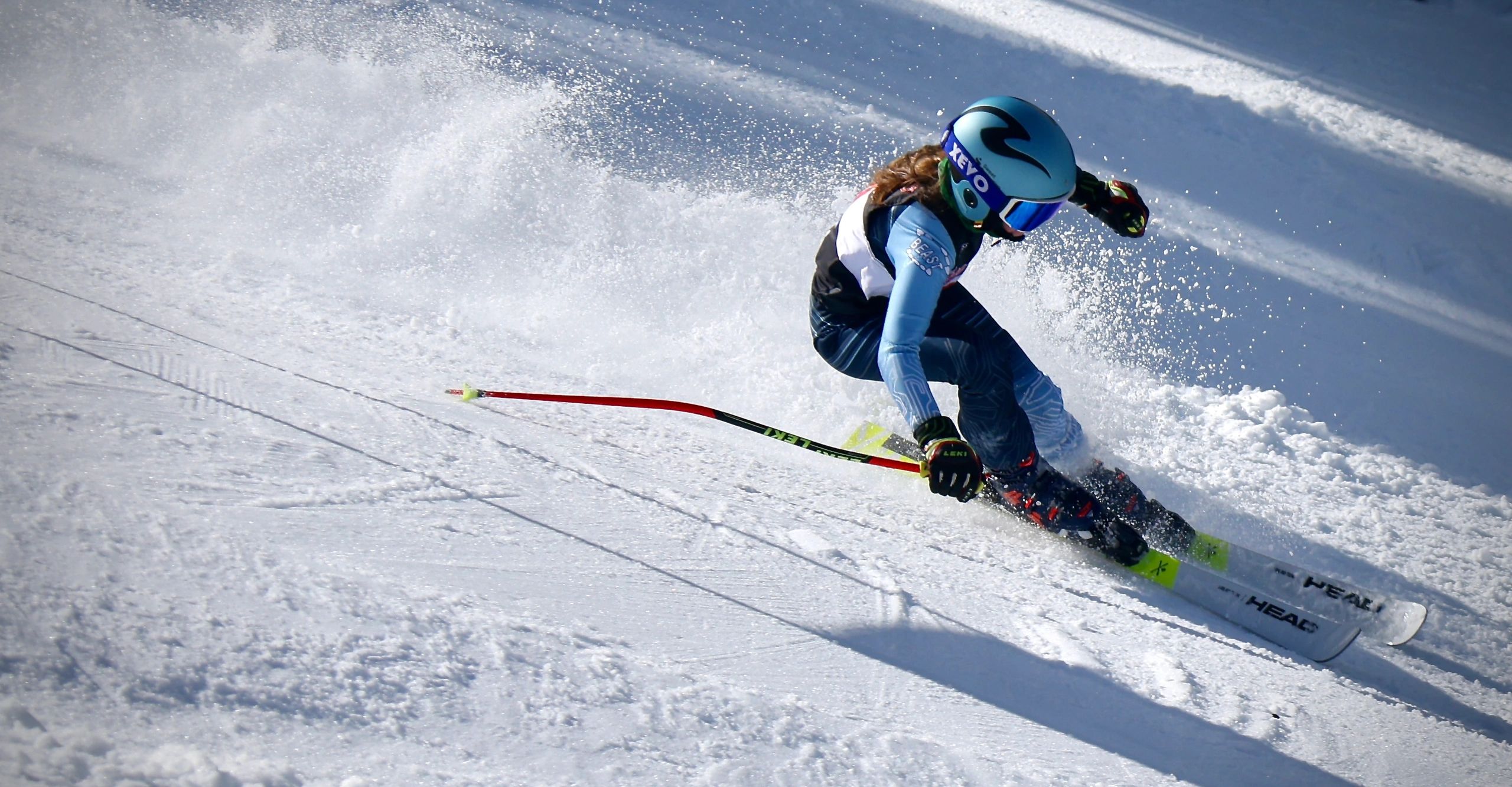 Ski racer making a sharp turn on a snowy slope, kicking up powder.